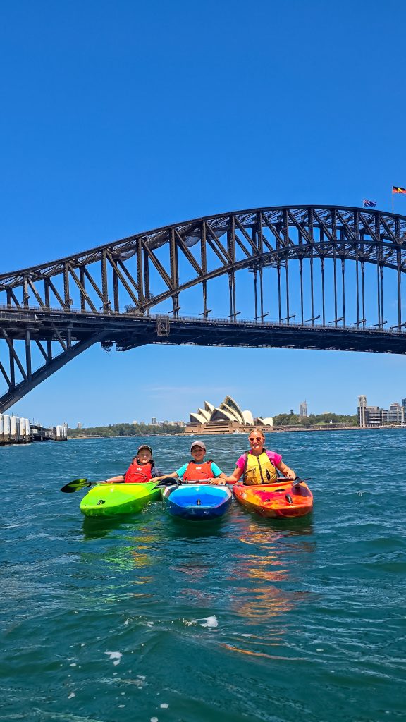 Mother smiling with two kids with sydney harbour bridge and opera hosue in background